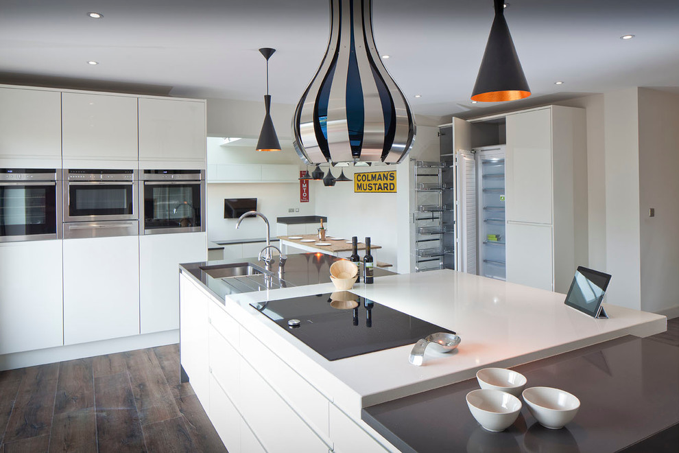 Große Moderne Wohnküche mit Einbauwaschbecken, flächenbündigen Schrankfronten, beigen Schränken, Quarzit-Arbeitsplatte, Küchengeräten aus Edelstahl, dunklem Holzboden und Kücheninsel in Hertfordshire