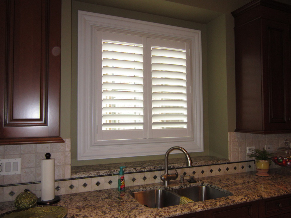 Inspiration for a transitional kitchen remodel in Chicago with a double-bowl sink, raised-panel cabinets, dark wood cabinets, quartzite countertops, beige backsplash and ceramic backsplash