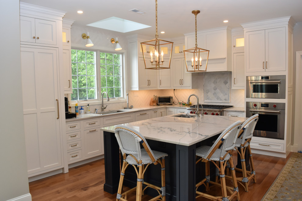 Inspiration for a large traditional l-shaped eat-in kitchen in Philadelphia with a farmhouse sink, recessed-panel cabinets, blue cabinets, quartzite benchtops, white splashback, porcelain splashback, panelled appliances, dark hardwood floors, with island, brown floor and blue benchtop.
