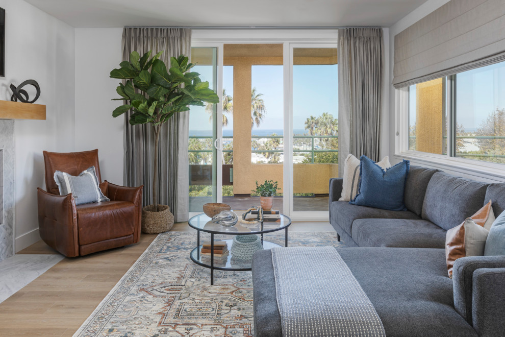 This is an example of a beach style family room in Los Angeles with white walls and light hardwood floors.