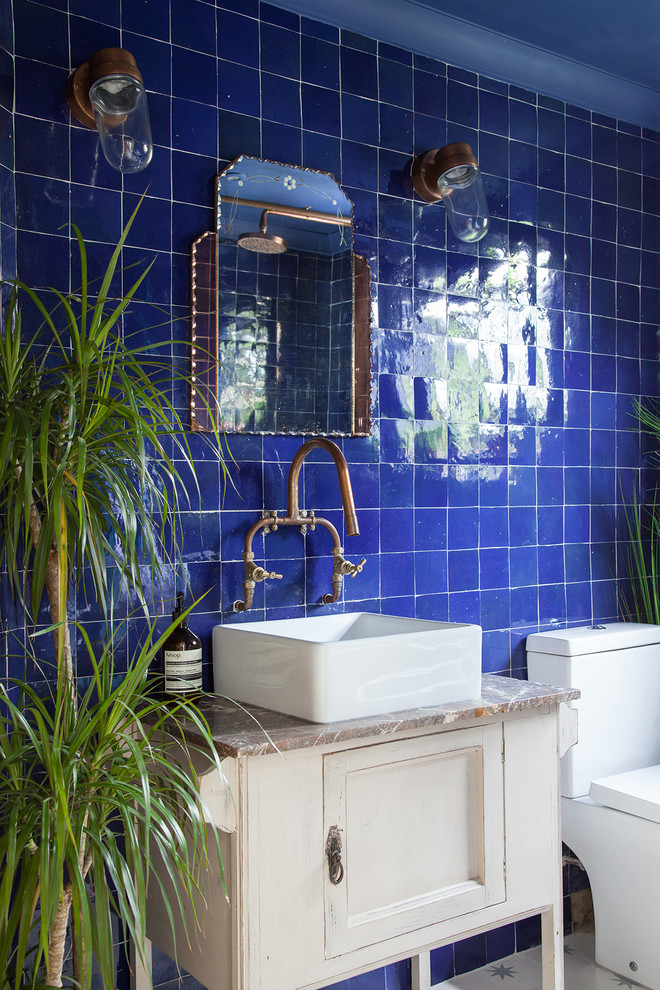 Small eclectic kids bathroom in London with furniture-like cabinets, beige cabinets, a freestanding tub, a shower/bathtub combo, a one-piece toilet, blue tile, cement tile, blue walls, cement tiles, a console sink, marble benchtops, white floor and a shower curtain.