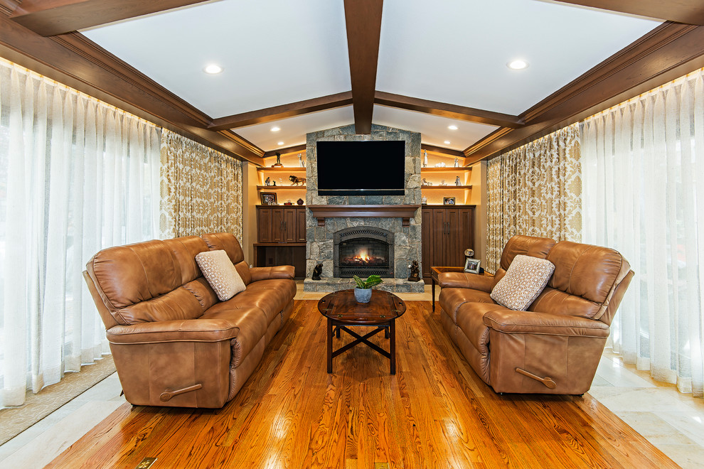 Inspiration for a mid-sized traditional open concept family room in Other with brown walls, medium hardwood floors, a standard fireplace, a stone fireplace surround, a wall-mounted tv and brown floor.