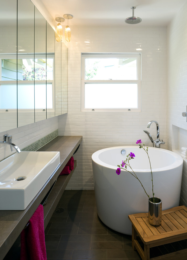 Inspiration for a small modern bathroom in Los Angeles with flat-panel cabinets, a japanese tub, a shower/bathtub combo, a bidet, white tile, porcelain tile, white walls, limestone floors, a vessel sink and limestone benchtops.