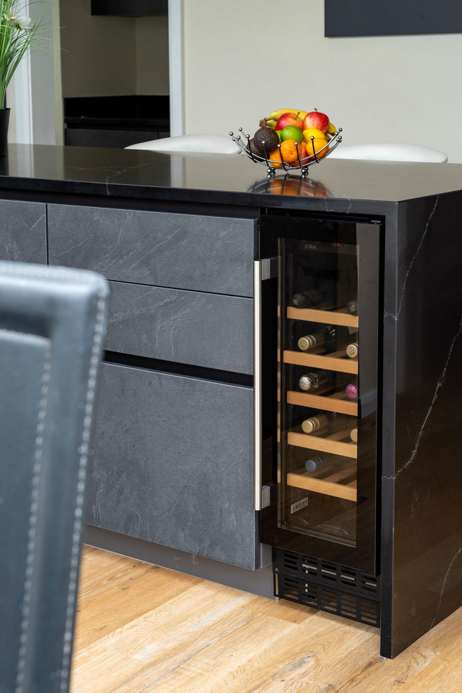 Medium sized contemporary l-shaped kitchen/diner in Oxfordshire with a single-bowl sink, flat-panel cabinets, grey cabinets and black appliances.