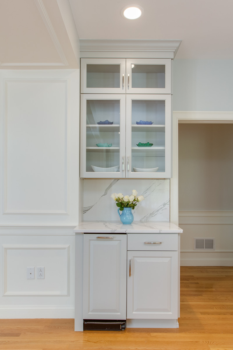Large transitional l-shaped medium tone wood floor open concept kitchen photo in Boston with an undermount sink, raised-panel cabinets, gray cabinets, quartz countertops, stone slab backsplash, paneled appliances and an island