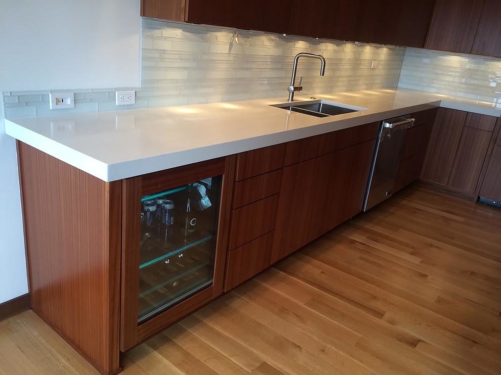 Mid-sized contemporary l-shaped eat-in kitchen in Miami with an undermount sink, flat-panel cabinets, medium wood cabinets, quartzite benchtops, white splashback, glass tile splashback, stainless steel appliances, medium hardwood floors and with island.