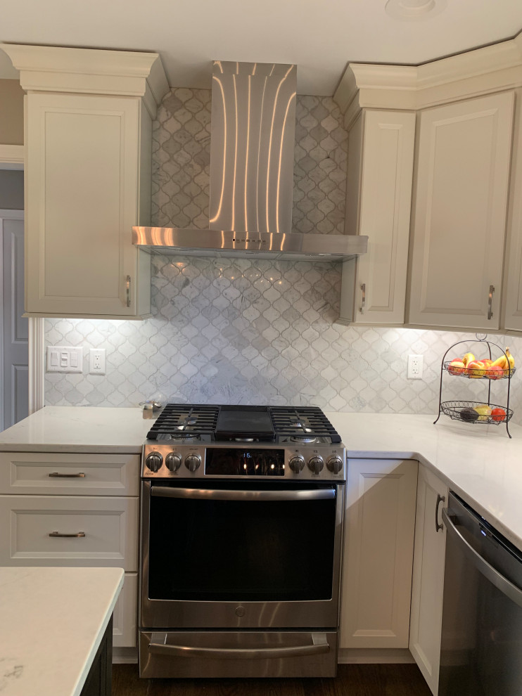 Eat-in kitchen - mid-sized transitional l-shaped medium tone wood floor and brown floor eat-in kitchen idea in Cincinnati with an undermount sink, flat-panel cabinets, white cabinets, quartz countertops, white backsplash, marble backsplash, stainless steel appliances, an island and white countertops