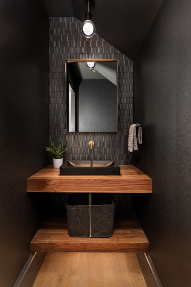 Exemple d'un WC et toilettes chic avec un carrelage noir et un plan de toilette en bois.