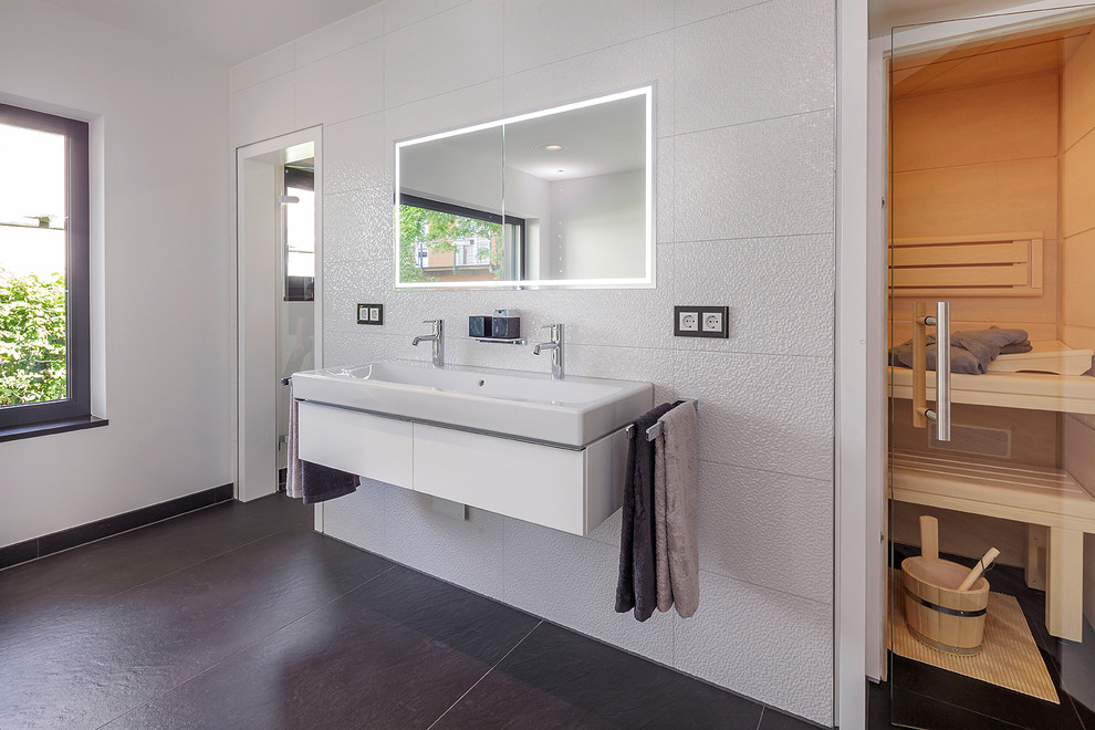Inspiration for a large contemporary bathroom in Nuremberg with flat-panel cabinets, white cabinets, white tile, white walls, slate floors, a trough sink and with a sauna.