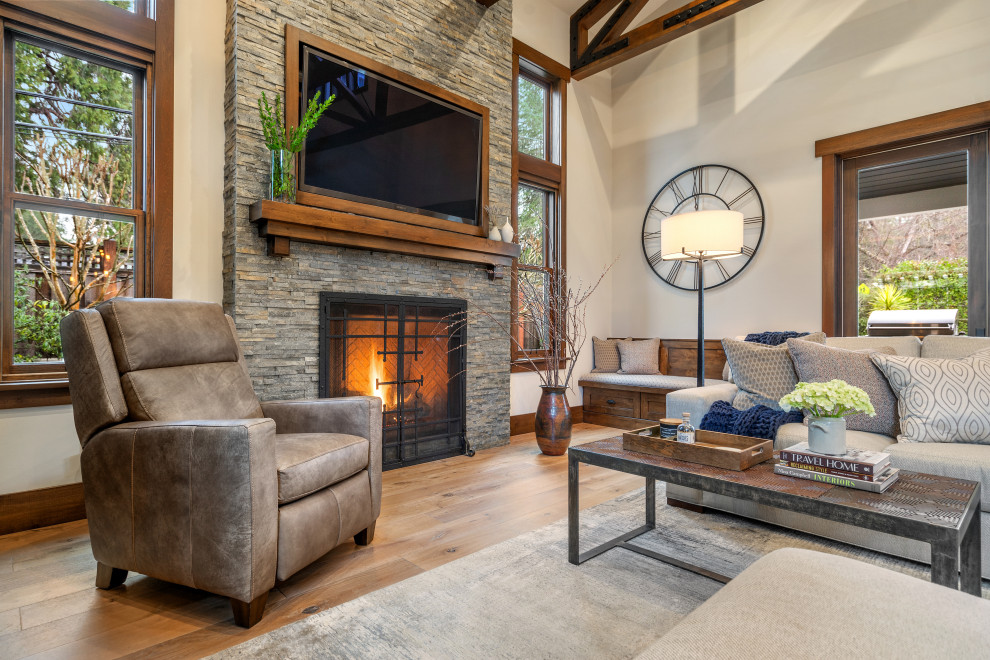 Mid-sized country open concept living room in San Francisco with beige walls, light hardwood floors, a standard fireplace, a wall-mounted tv and exposed beam.