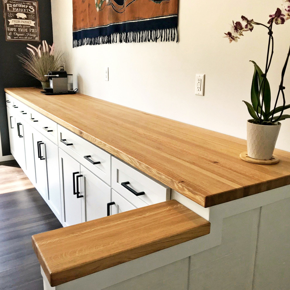 Immagine di una cucina minimalista di medie dimensioni con lavello da incasso, ante con riquadro incassato, ante bianche, top in legno, elettrodomestici in acciaio inossidabile, pavimento marrone e top marrone