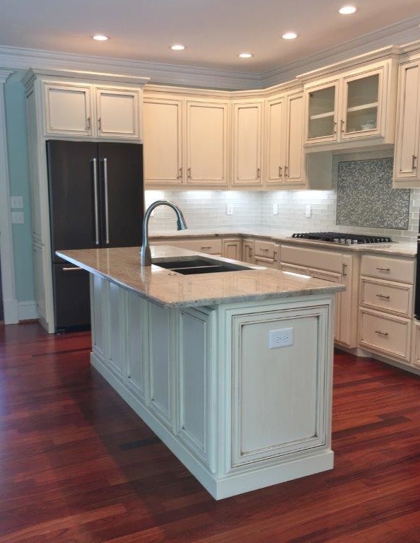 Inspiration for a mid-sized transitional l-shaped separate kitchen in Raleigh with a double-bowl sink, beaded inset cabinets, beige cabinets, granite benchtops, grey splashback, glass tile splashback, black appliances, dark hardwood floors, with island, red floor and beige benchtop.