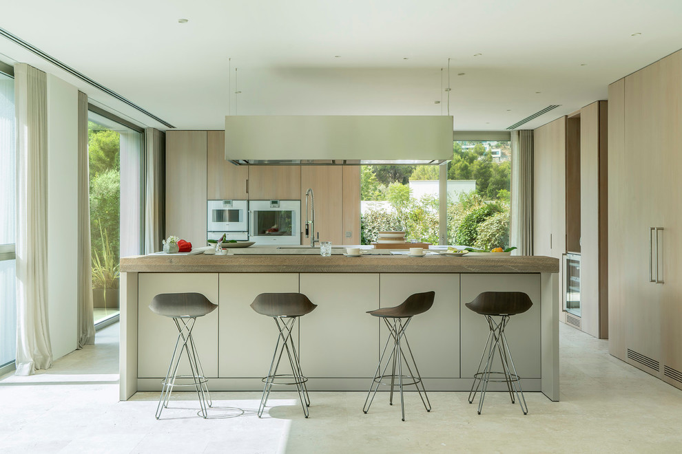Contemporary l-shaped kitchen in Palma de Mallorca with an undermount sink, flat-panel cabinets, light wood cabinets, with island and beige floor.
