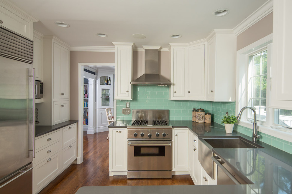 Inspiration for a traditional u-shaped separate kitchen in New York with a farmhouse sink, recessed-panel cabinets, white cabinets, stainless steel benchtops, green splashback, subway tile splashback, stainless steel appliances and medium hardwood floors.