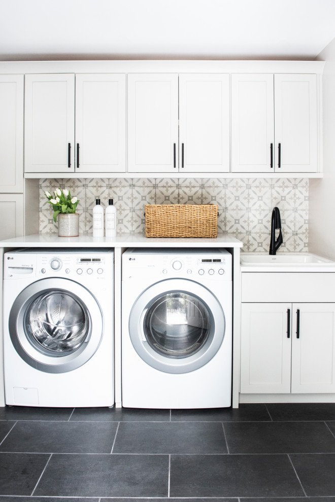 Transitional single-wall dedicated laundry room in Boston with a drop-in sink, shaker cabinets, white cabinets, grey walls, a side-by-side washer and dryer, black floor and white benchtop.