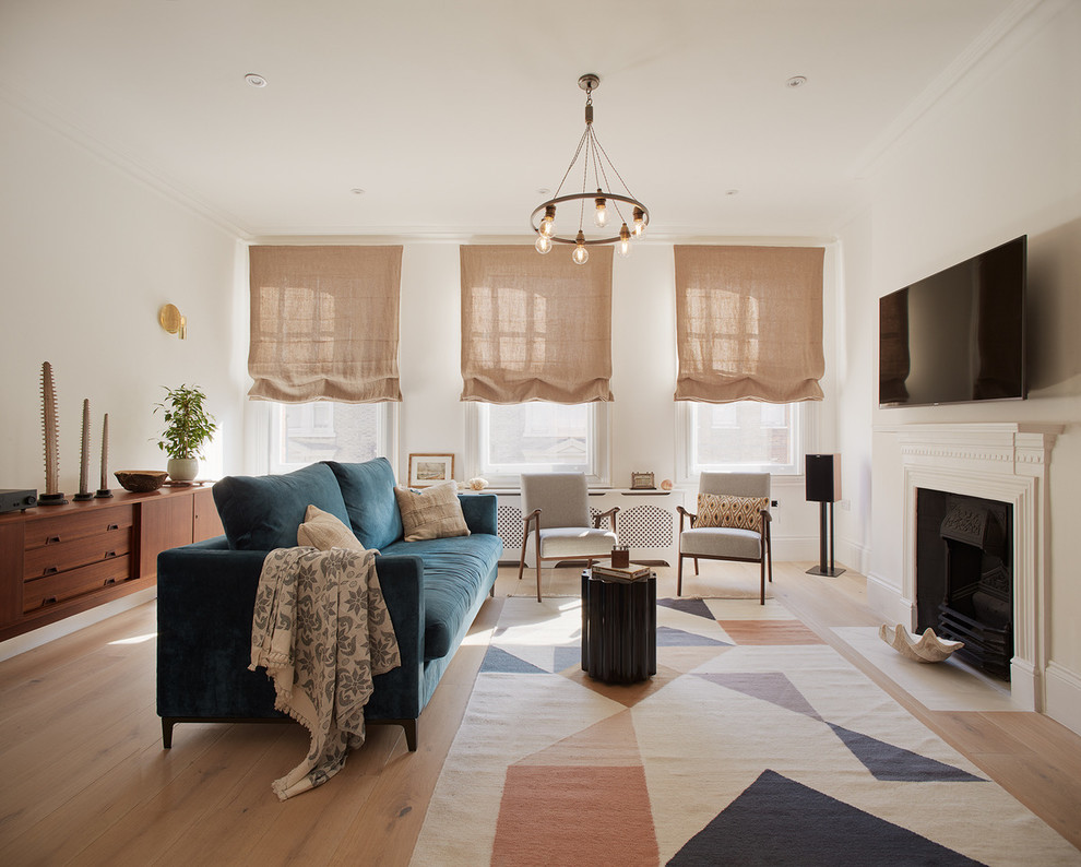 Inspiration for a medium sized scandinavian open plan games room in London with white walls, light hardwood flooring, a wall mounted tv, a standard fireplace and a plastered fireplace surround.