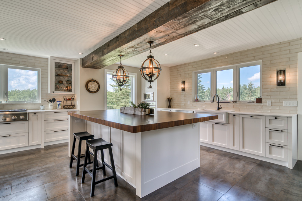 Inspiration for a large country galley open plan kitchen in Calgary with a farmhouse sink, shaker cabinets, white cabinets, wood benchtops, beige splashback, ceramic splashback, stainless steel appliances, ceramic floors, multiple islands, grey floor and brown benchtop.