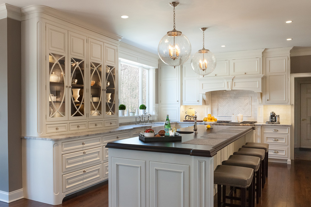 Design ideas for a traditional l-shaped eat-in kitchen in New York with glass-front cabinets, white cabinets, wood benchtops, with island, an undermount sink, white splashback and dark hardwood floors.