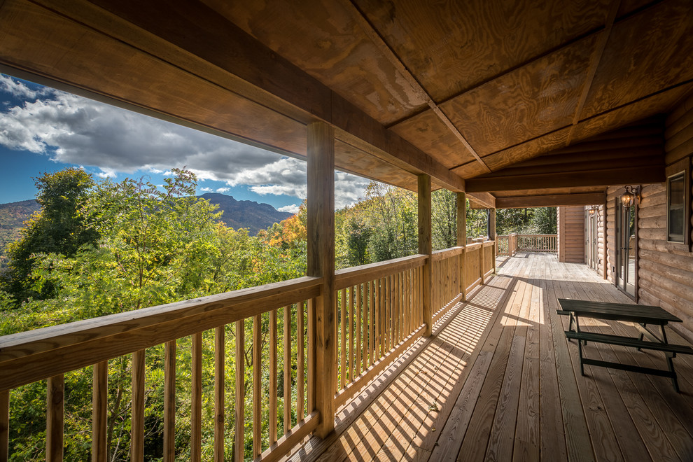Huge mountain style backyard deck photo in Charlotte with a roof extension