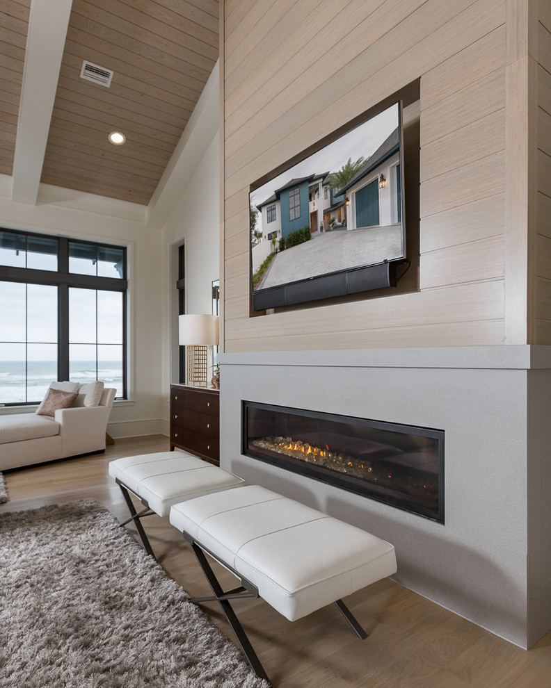 This is an example of a mid-sized beach style formal enclosed living room in Miami with white walls, light hardwood floors, a standard fireplace, a concrete fireplace surround and a wall-mounted tv.