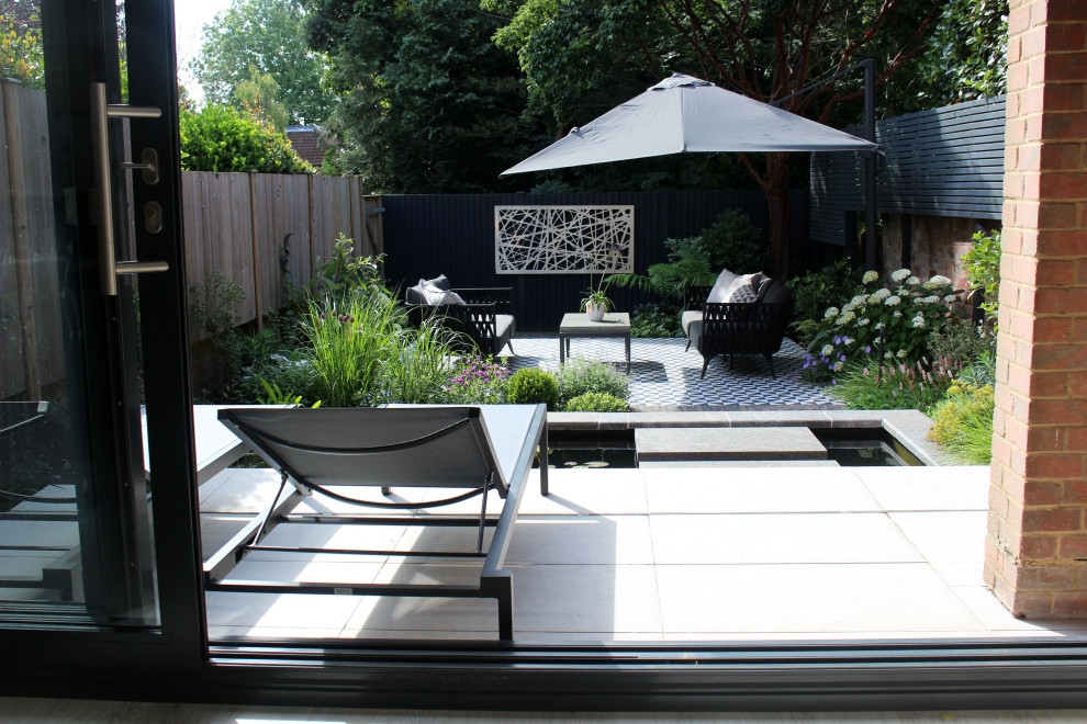 Immagine di un piccolo patio o portico minimal in cortile con pavimentazioni in pietra naturale e un parasole