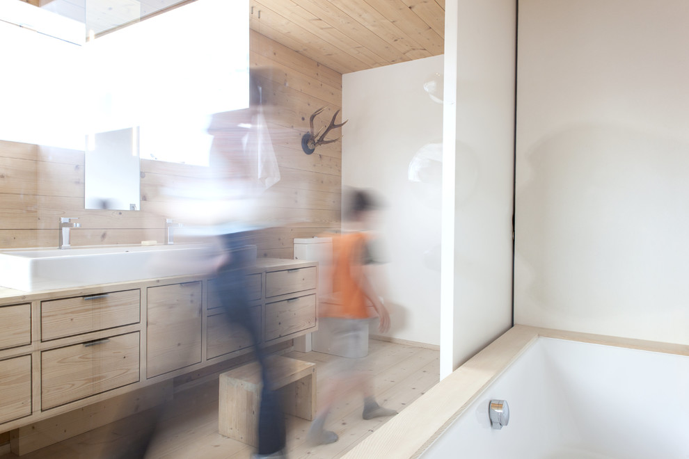 Badezimmer En Suite With flächenbündigen Schrankfronten, hellen Holzschränken, freistehender Badewanne, bodengleicher Dusche, Wandtoilette, beiger Wandfarbe, gebeiztem Holzboden, Aufsatzwaschbecken, Waschtisch aus Holz, beigem Boden and offener Dusche in Stuttgart