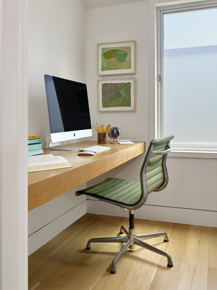 Idee per uno studio minimalista con pareti bianche, parquet chiaro e scrivania incassata