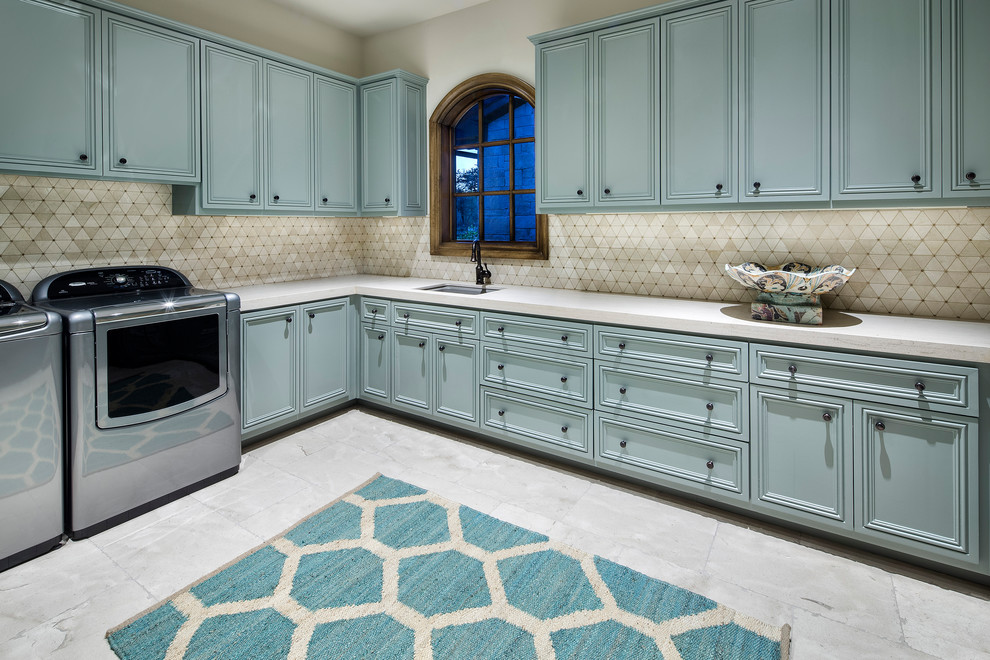 Inspiration for a large traditional l-shaped dedicated laundry room in Austin with an undermount sink, recessed-panel cabinets, turquoise cabinets, beige walls, a side-by-side washer and dryer and beige benchtop.