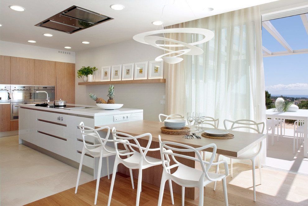 This is an example of a large contemporary galley eat-in kitchen in Barcelona with flat-panel cabinets, white cabinets, solid surface benchtops, stainless steel appliances and with island.
