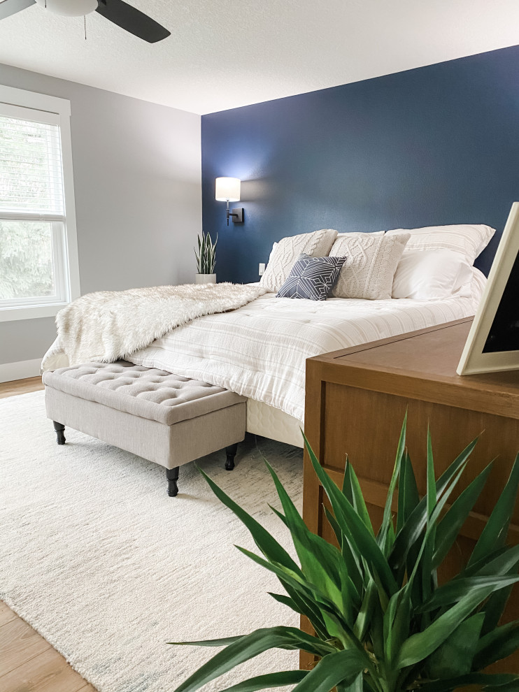 Imagen de dormitorio principal actual grande con paredes azules, suelo laminado y suelo marrón