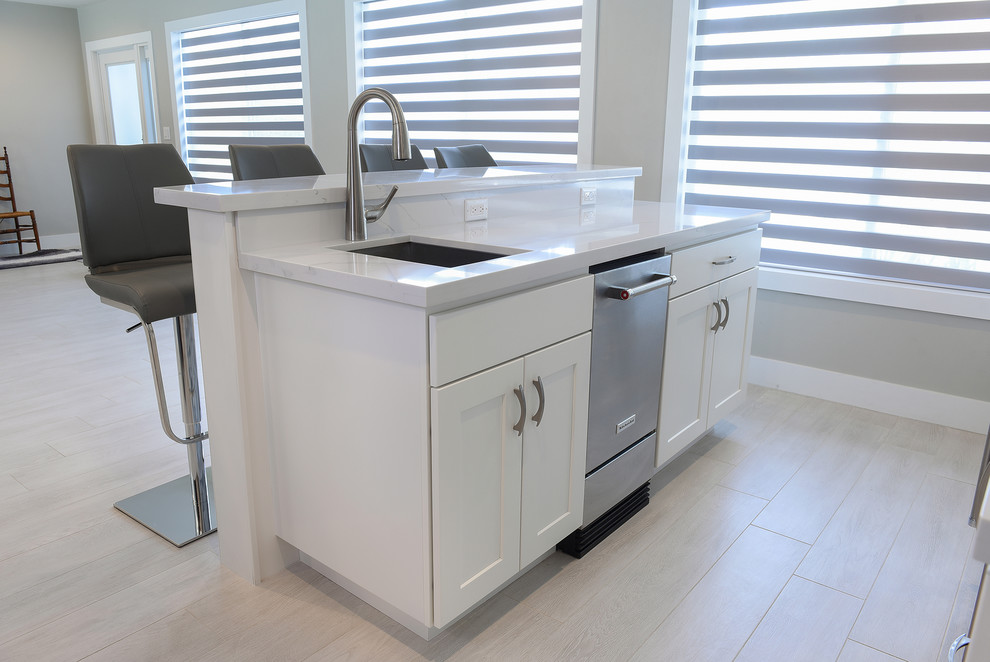 Open concept kitchen - large transitional l-shaped porcelain tile and gray floor open concept kitchen idea in Miami with a farmhouse sink, shaker cabinets, gray cabinets, quartz countertops, gray backsplash, marble backsplash, stainless steel appliances and two islands