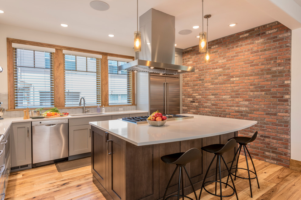 Mid-sized transitional l-shaped eat-in kitchen in Denver with an undermount sink, shaker cabinets, grey cabinets, quartz benchtops, white splashback, glass tile splashback, stainless steel appliances, light hardwood floors, with island, yellow floor and white benchtop.
