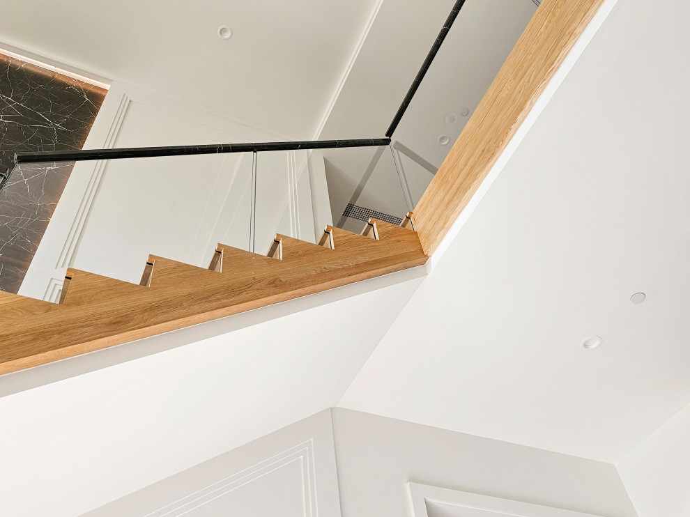Ejemplo de escalera suspendida actual extra grande con escalones de madera, contrahuellas de madera, barandilla de varios materiales y boiserie