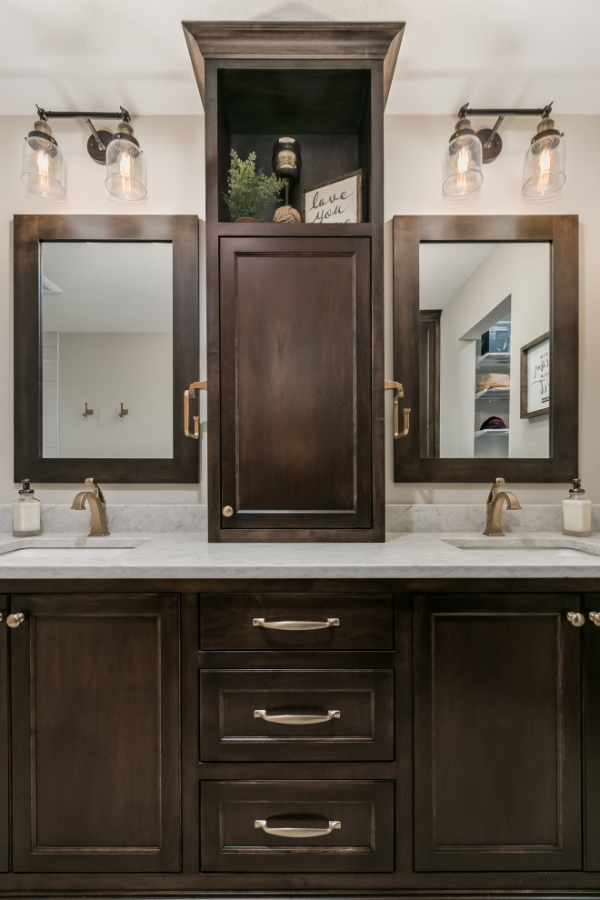 This is an example of a mid-sized beach style master bathroom in Minneapolis with flat-panel cabinets, dark wood cabinets, a drop-in tub, a shower/bathtub combo, a one-piece toilet, beige tile, ceramic tile, beige walls, laminate floors, a drop-in sink, marble benchtops, beige floor, a hinged shower door, multi-coloured benchtops, a double vanity and a floating vanity.