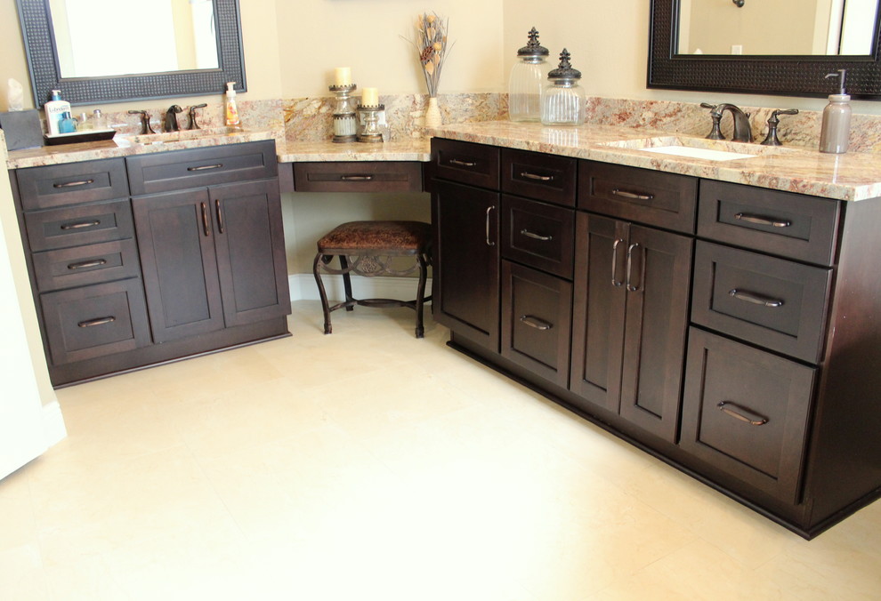 Photo of a transitional master bathroom in Tampa with recessed-panel cabinets, dark wood cabinets, granite benchtops, beige tile, porcelain floors, an undermount sink and porcelain tile.