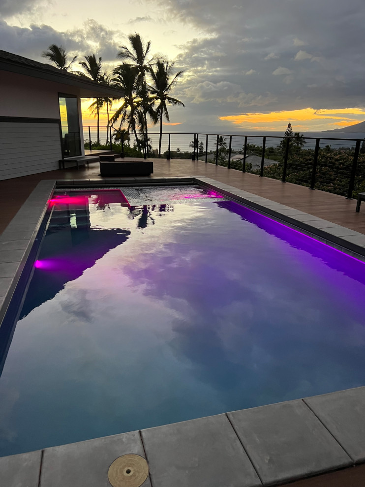 Photo of an expansive modern side yard rectangular aboveground pool in Hawaii with a hot tub and decking.