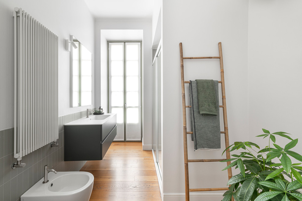 Exempel på ett mellanstort modernt vit vitt en-suite badrum, med släta luckor, gröna skåp, en dusch i en alkov, en vägghängd toalettstol, grön kakel, stickkakel, vita väggar, ljust trägolv, ett integrerad handfat, bänkskiva i akrylsten och dusch med skjutdörr
