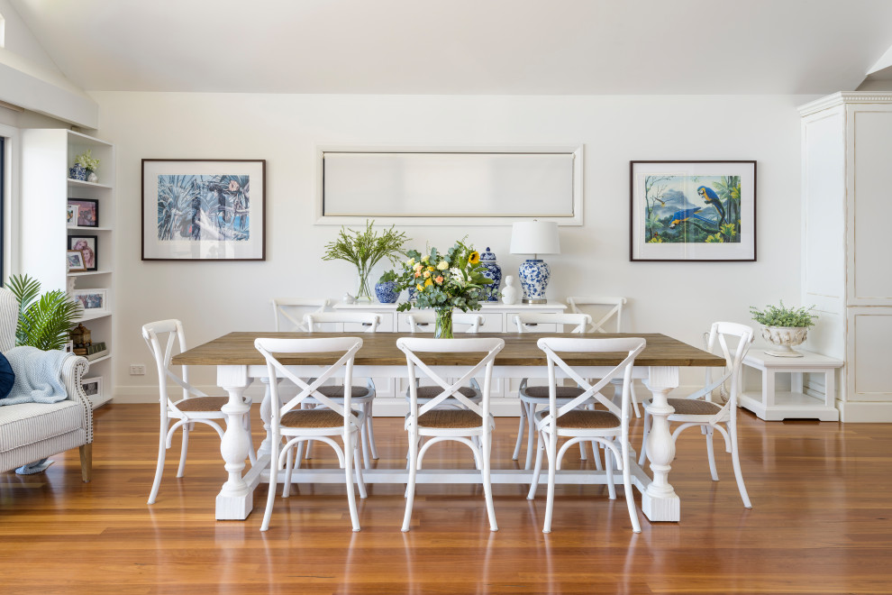 Design ideas for a beach style dining room in Sydney with white walls, medium hardwood floors and brown floor.
