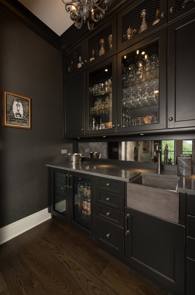 Mid-sized traditional single-wall wet bar in Chicago with an integrated sink, glass-front cabinets, dark wood cabinets, quartz benchtops, mirror splashback, dark hardwood floors, brown floor and grey benchtop.