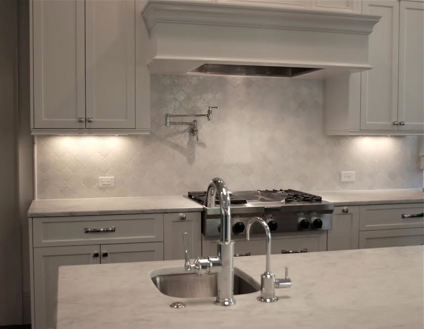 Mid-sized trendy kitchen photo with an undermount sink, shaker cabinets, white cabinets, marble countertops, white backsplash, stainless steel appliances and an island