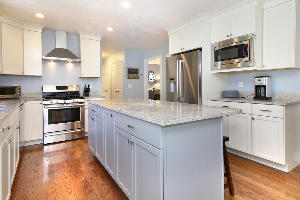 Mid-sized transitional u-shaped open plan kitchen in Portland Maine with a single-bowl sink, raised-panel cabinets, white cabinets, granite benchtops, blue splashback, stainless steel appliances and medium hardwood floors.