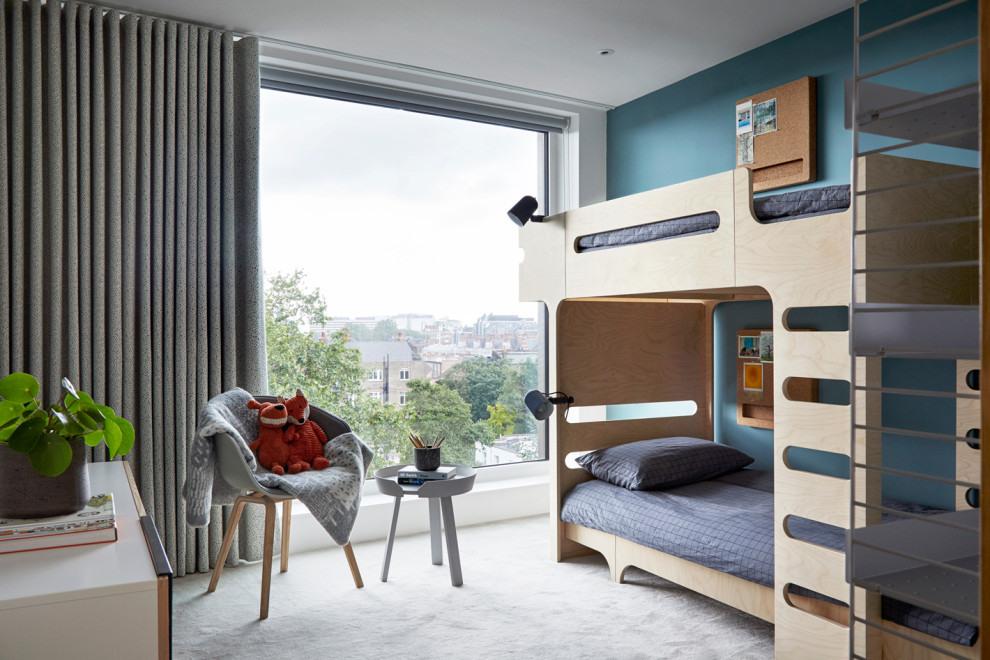 Mid-sized scandinavian gender-neutral kids' bedroom in London with blue walls, carpet and grey floor for kids 4-10 years old.