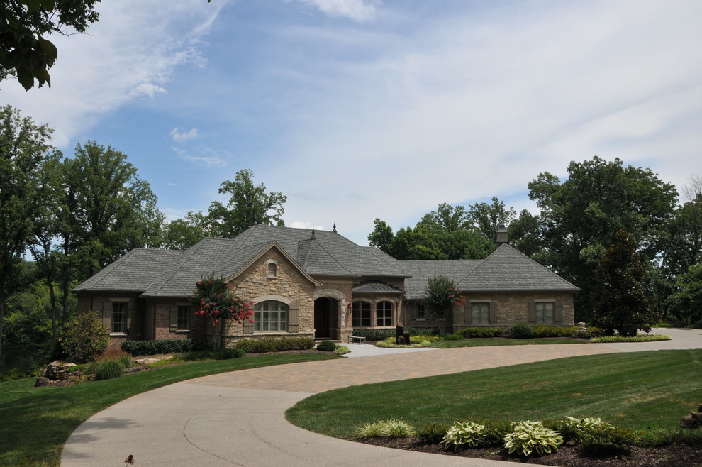 Design ideas for a large traditional one-storey beige exterior in Indianapolis with stone veneer and a hip roof.