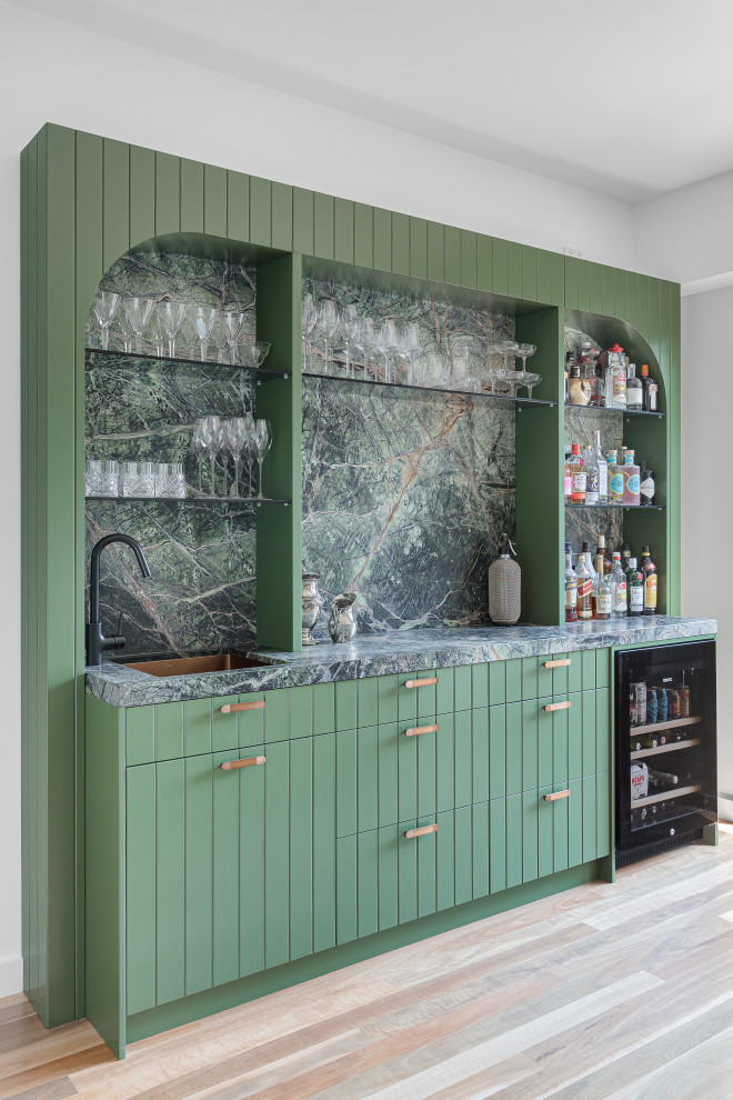 Contemporary single-wall wet bar in Melbourne with an undermount sink, green cabinets, marble benchtops, multi-coloured splashback, marble splashback, medium hardwood floors, brown floor and multi-coloured benchtop.