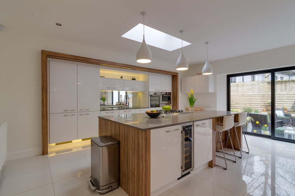 Mid-sized contemporary open plan kitchen in Belfast with white cabinets, stainless steel appliances, porcelain floors, flat-panel cabinets and with island.