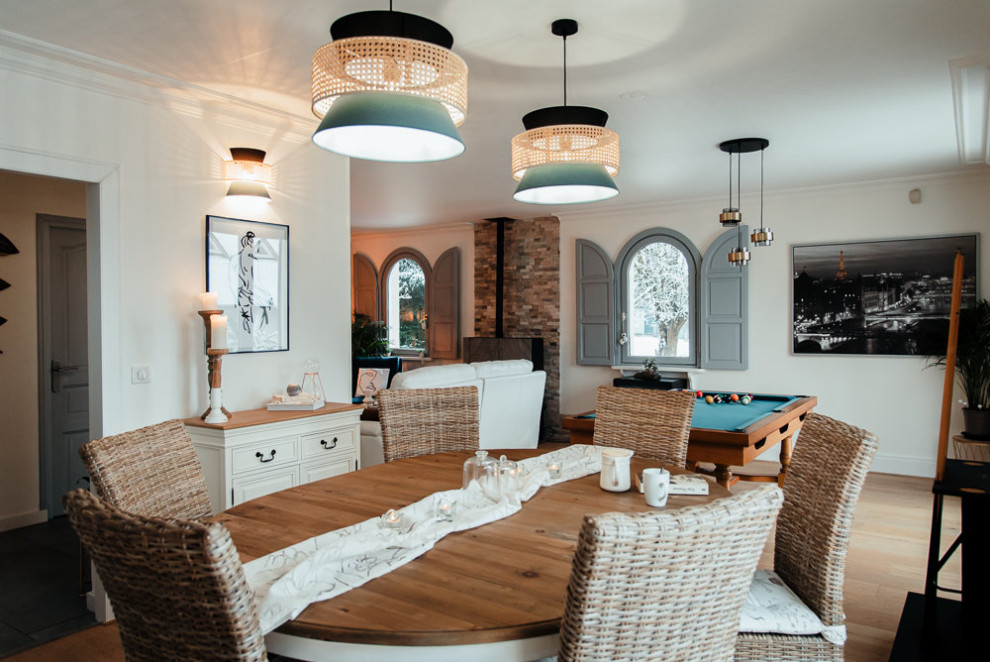 Foto di una sala da pranzo aperta verso il soggiorno chic di medie dimensioni con pareti bianche, parquet chiaro e stufa a legna