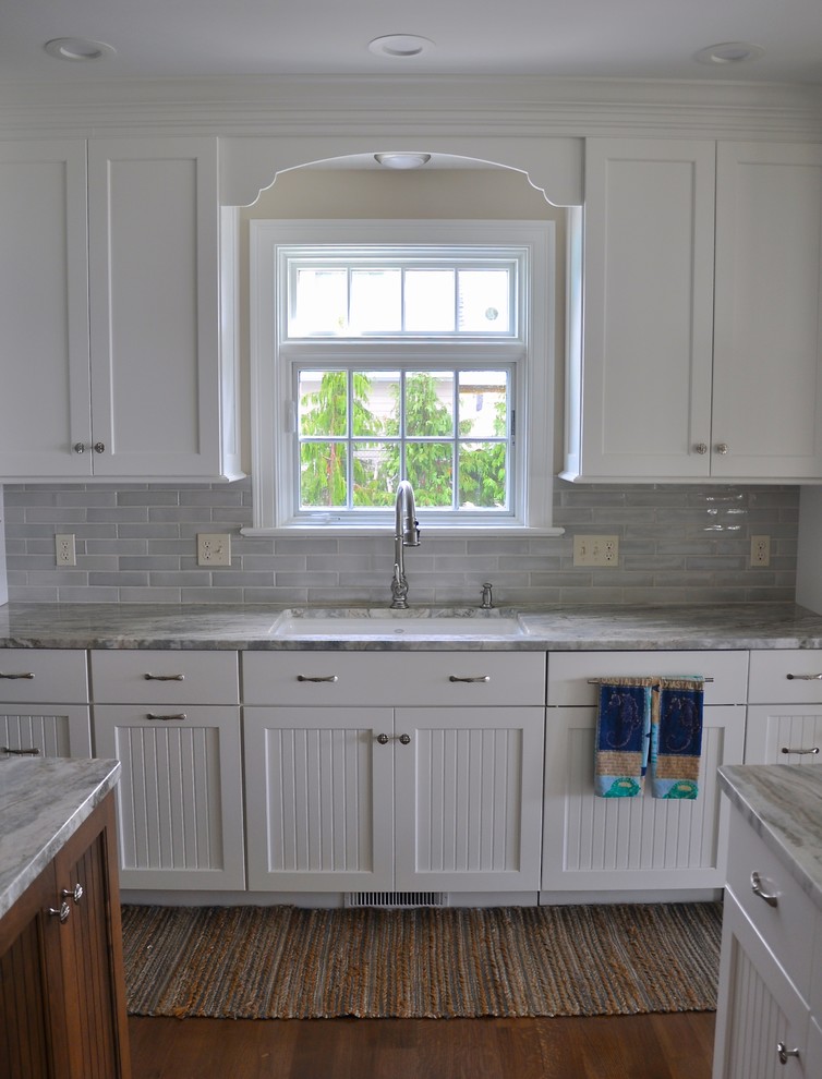 Expansive beach style eat-in kitchen in Providence with a single-bowl sink, recessed-panel cabinets, white cabinets, quartzite benchtops, blue splashback, glass tile splashback, stainless steel appliances, dark hardwood floors, with island and beige floor.