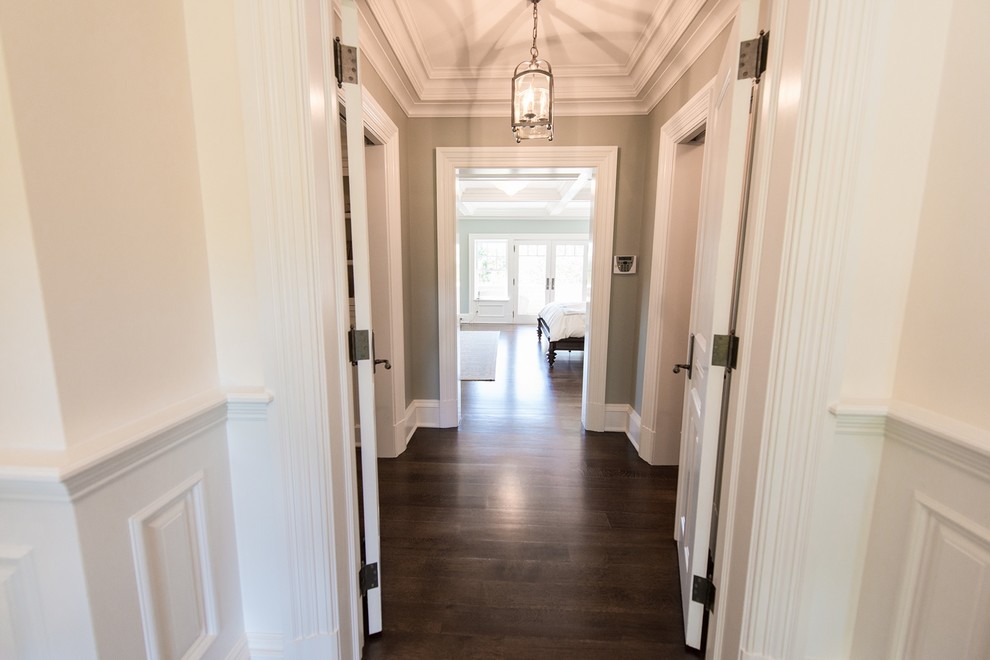 This is an example of an expansive traditional hallway in New York with white walls and dark hardwood floors.