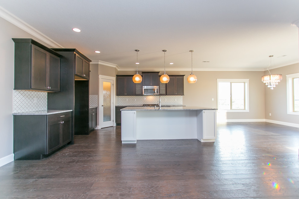 Open concept kitchen - mid-sized transitional l-shaped dark wood floor open concept kitchen idea in Seattle with an undermount sink, shaker cabinets, dark wood cabinets, granite countertops, white backsplash, porcelain backsplash, stainless steel appliances and an island