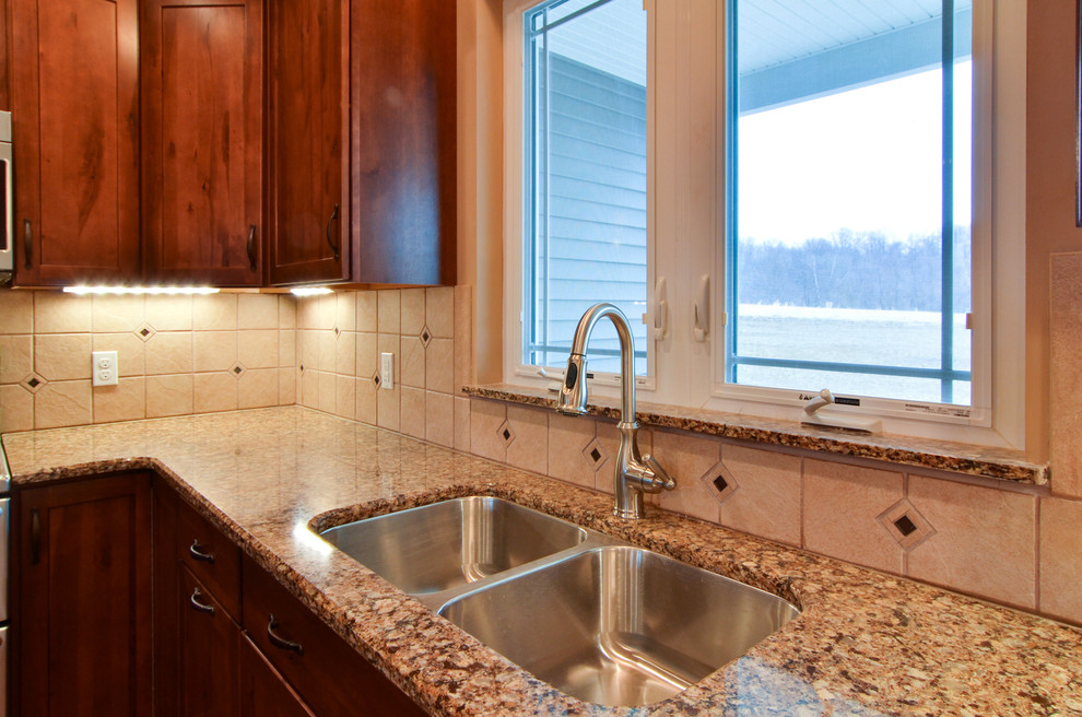 Open concept kitchen - mid-sized rustic l-shaped medium tone wood floor open concept kitchen idea with a double-bowl sink, shaker cabinets, medium tone wood cabinets, quartz countertops, beige backsplash, ceramic backsplash, stainless steel appliances, beige walls and an island